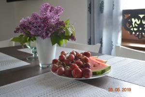un plato de fruta en una mesa con un jarrón de flores en Zacisze, en Biały Dunajec
