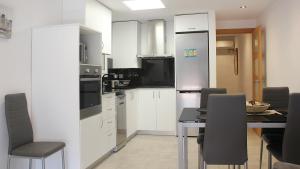 a kitchen with white cabinets and a table and chairs at Apartament Margarit in Girona