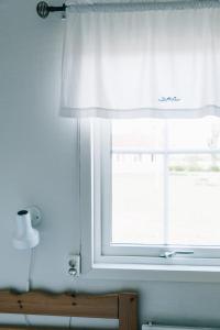 uma janela com uma cortina branca num quarto em Visingsö Vandrarhem em Visingsö