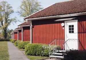 a red building with a white door and stairs on it at Visingsö Vandrarhem in Visingsö
