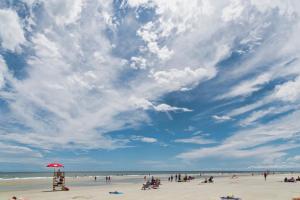 a group of people on a beach with a red umbrella at Saint Andrews Common 1774 in Hilton Head Island