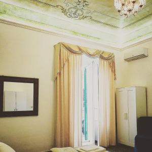 1 dormitorio con ventana con cortinas y espejo en Le Suite del Teatro cucinino privato, en Taranto
