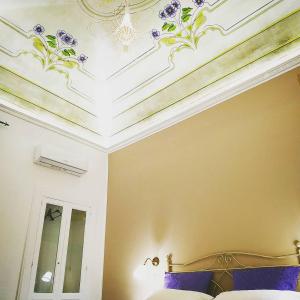 a bedroom with a bed and a ceiling with purple flowers at Le Suite del Teatro cucinino privato in Taranto