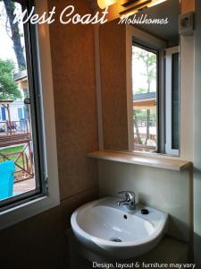 a bathroom with a sink and a mirror and a window at West Coast Mobilhome with XXL Terrace in Naturist Resort Solaris FKK in Poreč