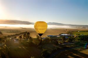 a yellow hot air balloon flying over a field at Yarra Valley Lodge in Wonga Park
