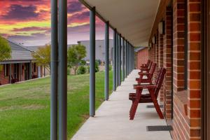 a row of wooden benches in front of a building at Blazing Stump Motel & Suites in Wodonga