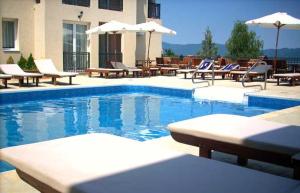 a swimming pool with lounge chairs and umbrellas at Sunny Hill Apartments & Aqua Park in Vrnjačka Banja