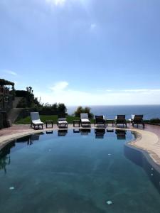 una piscina con bancos y el océano en el fondo en Villa la Dimora di Zoè, en Isquia