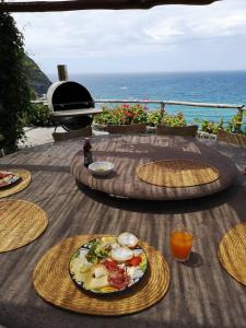 einen Tisch mit Teller mit Lebensmitteln auf einem Tisch mit dem Meer in der Unterkunft Villa la Dimora di Zoè in Ischia