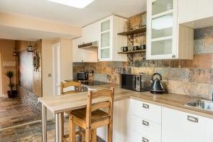 cocina con armarios blancos y mesa de madera en Deluxe Rustic Charlestown Themed Apartment, en St Austell