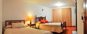 um quarto com 2 camas, um candeeiro e uma janela em Hospedaje El Mirador em Villa de Leyva