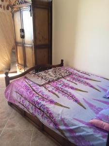 Una cama con un edredón morado encima. en Agami Apartment en Alexandría