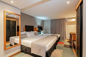 Habitación de hotel con 2 camas y espejo en Slaviero Curitiba Batel, en Curitiba