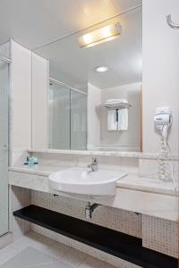 a bathroom with a sink, mirror, and bathtub at Slaviero Curitiba Batel in Curitiba