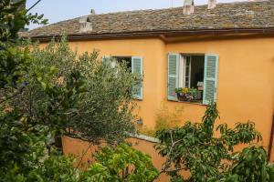 a yellow house with a window with flowers in it at Latu Corsu - Côté Corse - Gites et chambres d'hôtes au Cap Corse in Ersa