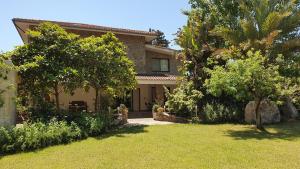 una casa con alberi e un prato di fronte ad essa di Villa Canu ad Alghero