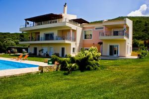 a large house with a swimming pool in front of it at BRINA'S LUXURY APARTMENTS in Áyioi Apóstoloi