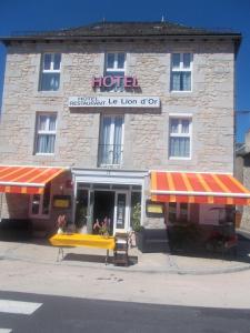 un hotel con toldos de rayas rojas y amarillas delante de él en le lion d'or, en Saint-Chély-d'Apcher