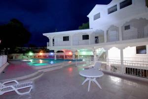 a white house with a pool and a table and chairs at Residence Royale Hôtel in Cap-Haïtien