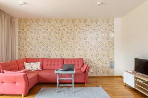 a living room with a pink couch and a laptop on a table at Kopu Vetrunges - Nida Apartments in Nida