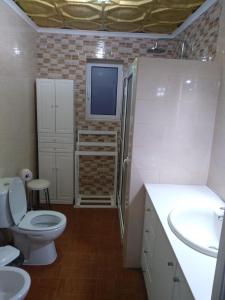 a bathroom with a toilet and a tv on the wall at Vivenda "Porto de Abrigo" in Biscoitos