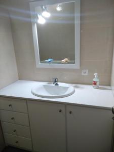 un bagno con un lavandino bianco e uno specchio di Vivenda "Porto de Abrigo" a Biscoitos