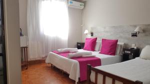 Habitación de hotel con 2 camas y almohadas rosas en Hotel Iris en Salta