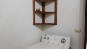 a bathroom with a toilet and a wooden shelf above it at OceanBlue Samara Lodge in Sámara