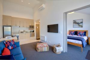 ein Wohnzimmer mit einem blauen Sofa und einem Bett in der Unterkunft Supreme Lakefront in Queenstown