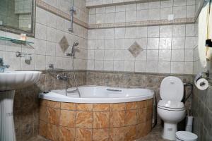a bathroom with a tub and a toilet and a sink at Vasilaras Hotel in Skala