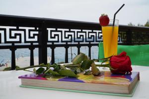 a book with a flower and a drink on a table at Vasilaras Hotel in Skala