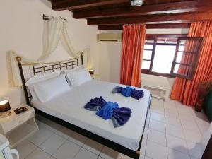 a bedroom with a white bed with blue robes on it at Vasilaras Hotel in Skala