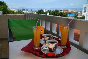 two glasses of orange juice and two cups on a table at Vasilaras Hotel in Skala