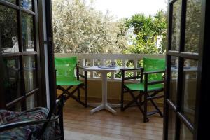 a patio with green chairs and a table at Vasilaras Hotel in Skala