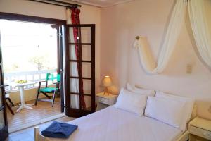 a bedroom with a bed and a balcony with a table at Vasilaras Hotel in Skala