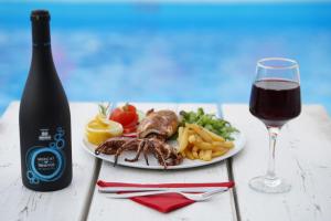 a plate of food and a glass of red wine at Vasilaras Hotel in Skala