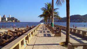 ein Strand mit Bänken und Menschen auf dem Wasser in der Unterkunft Lindo studio na Praia do Gonzaguinha in São Vicente