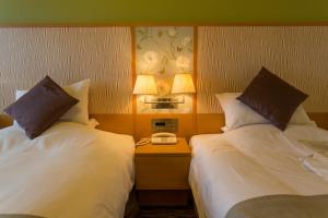 a hotel room with two beds and a table with a phone at Hotel Monterey Grasmere Osaka in Osaka