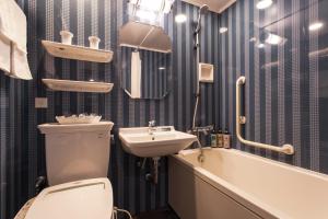 a bathroom with a toilet and a sink and a bath tub at Hotel Monterey Grasmere Osaka in Osaka