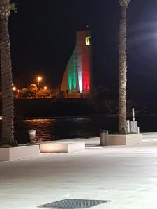 una torre de reloj con un letrero iluminado por la noche en La tana del pescatore, en Brindisi
