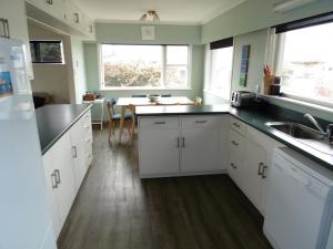 a kitchen with white cabinets and a sink and a table at Twin Palms in Waikanae