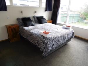 a bedroom with a bed with two towels on it at Twin Palms in Waikanae