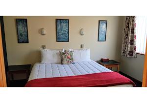 a bedroom with a large bed with a red blanket at Aspen Lodge Motel in Hanmer Springs