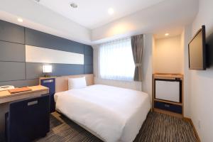 東京的住宿－上野入谷站船舶酒店，卧室配有白色的床和电视。