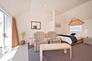 a bedroom with a bed and two chairs at Waimarie on Riverside Motel & Apartments in Nelson