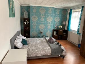 a bedroom with a bed and blue wallpaper at London budget Maisonette in London