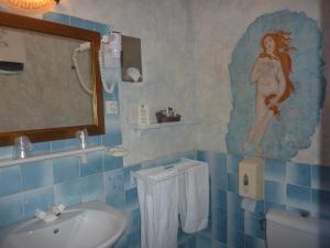 La salle de bains est pourvue de carrelage bleu, d'un lavabo et d'un miroir. dans l'établissement Hôtel du Fiacre, à Carpentras