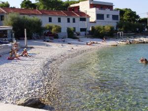 a group of people sitting on a beach near the water at Holiday home Boris - close to sea in Slatine