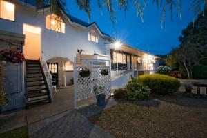 Uma casa branca com um portão à frente. em Waimarie on Riverside Motel & Apartments em Nelson