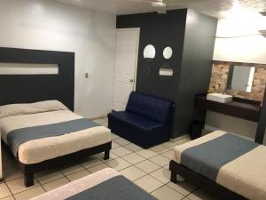 um quarto com 2 camas e uma cadeira azul em Hotel Raga Inn em Tamasopo